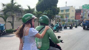 Vietnam ho chi minh città 23.05.2024 motociclo Taxi afferrare asiatico autista prende europeo giovane donna su un' viaggio per mossa in giro il città video