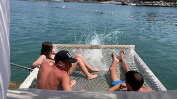 Teenagers at a camp by the sea. group of teenagers in a camp on the beach, relaxing together, swimming, sitting on a net over the water in Albania video