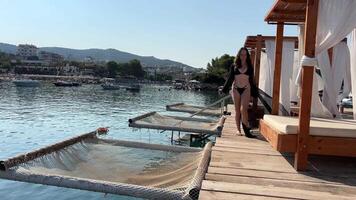 A teenage girl rests on the sea, swims in a black pareo, sits on her phone, relaxes on a luxury beach, several different videos of the travel process