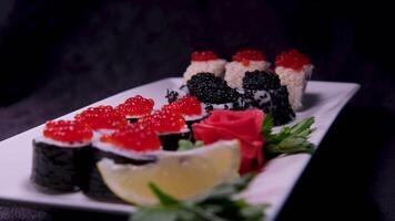 Sushi with caviar ready sushi rolls lie on a plate and rotate 360 degrees on black background video