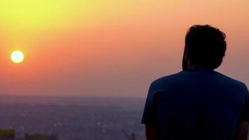 une Jeune homme est en train de regarder le coucher du soleil lent mouvement video