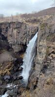 een teder waterval watervallen van de kant van een robuust rots vorming video