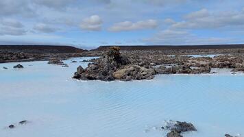 The contrast of blue lagoon water against black volcanic rocks in Iceland video