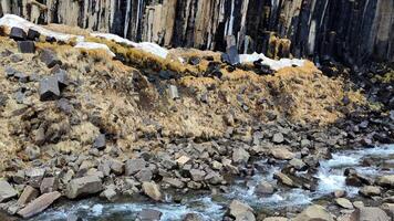 A small river winds its way through striking hexagonal basalt formations video