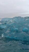 A vertical close-up shot capturing the intricate details of a crystal ice formation in a glacier lake video