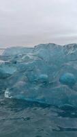 A vertical close-up shot capturing the intricate details of a crystal ice formation in a glacier lake video