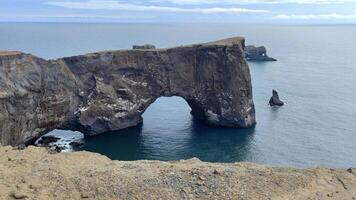 een opvallend hol rots vorming Aan een strand door de oceaan in IJsland. video