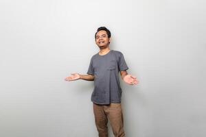 Young Asian asian man is confused when standing over white wall. Looking at camera. photo