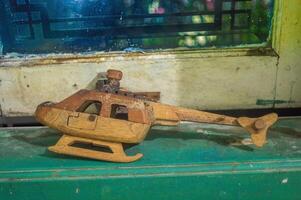 a broken toy or craft helicopter made of wood on the edge of a wooden window frame photo