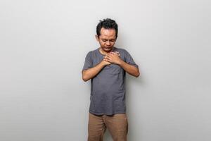 an Asian man holding one side of his chest because of chest pain or shortness of breath photo
