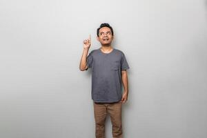 an asian man in gray is getting an idea while looking and pointing upwards isolated on white background photo