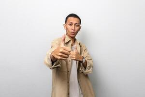 Asian man in tan jacket with like or thumb up hand gesture showing his best photo