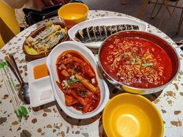 one table filled with Korean food consisting of kimbap, ramyeon, tteokbokki, and gimmari photo