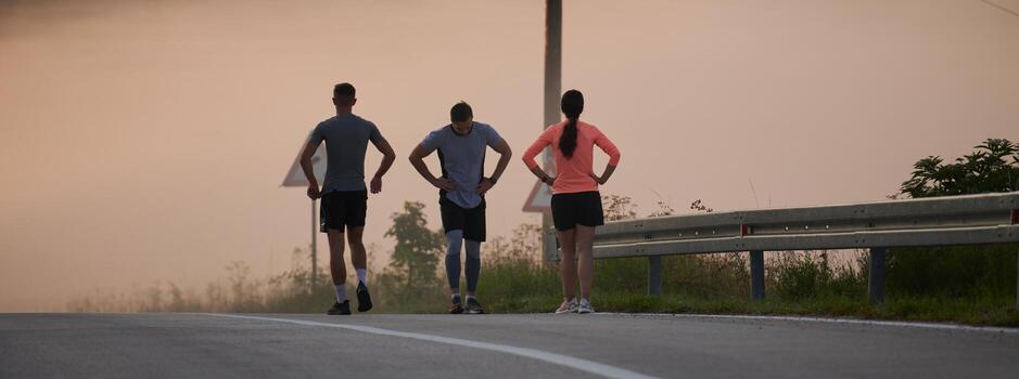 A group of friends, athletes, and joggers embrace the early morning hours as they run through the misty dawn, energized by the rising sun and surrounded by the tranquil beauty of nature photo