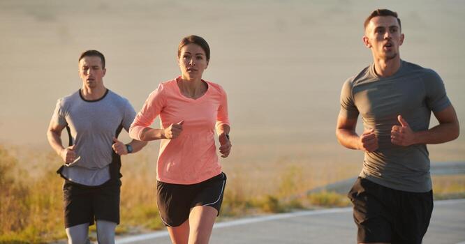 A group of friends, athletes, and joggers embrace the early morning hours as they run through the misty dawn, energized by the rising sun and surrounded by the tranquil beauty of nature photo