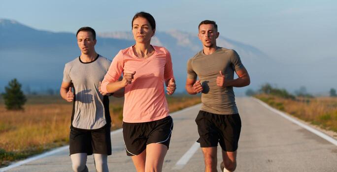 A group of friends, athletes, and joggers embrace the early morning hours as they run through the misty dawn, energized by the rising sun and surrounded by the tranquil beauty of nature photo