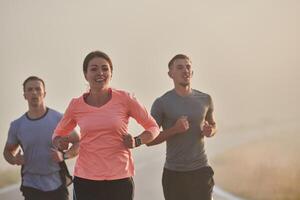 A group of friends, athletes, and joggers embrace the early morning hours as they run through the misty dawn, energized by the rising sun and surrounded by the tranquil beauty of nature photo