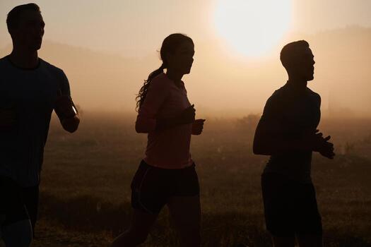 A group of friends, athletes, and joggers embrace the early morning hours as they run through the misty dawn, energized by the rising sun and surrounded by the tranquil beauty of nature photo