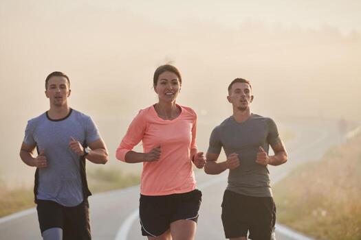 A group of friends, athletes, and joggers embrace the early morning hours as they run through the misty dawn, energized by the rising sun and surrounded by the tranquil beauty of nature photo