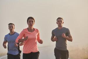 A group of friends, athletes, and joggers embrace the early morning hours as they run through the misty dawn, energized by the rising sun and surrounded by the tranquil beauty of nature photo