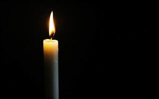 Burning white candle on black background. Close-up photo. With copy space. Image for memory of events and people photo