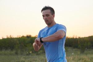 Sunny Run. Athlete Checks Smartwatch While Running in the Sun. photo