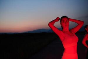 atleta huelgas un actitud en iluminado en rojo Noche resplandor foto