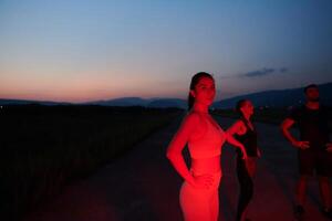 atleta huelgas un actitud en iluminado en rojo Noche resplandor foto
