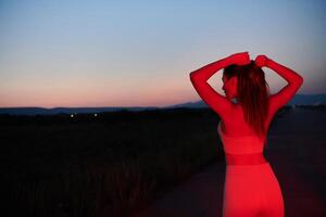 Athlete Strikes a Pose in Red-Lit Nighttime Glow photo