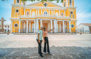 Two young tourists taking selfies in the cathedral of Granada, Nicaragua. Happy tourists taking selfies in a colorful colonial cathedral photo