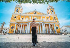 Portrait of a beautiful tourist girl in front of the cathedral in Granada, Nicaragua. Portrait of happy girl in front of a cathedral in a tourist square photo