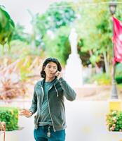 Young man gesturing and talking on the phone in a park. Latin guy talking on cell phone outdoors photo