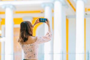 Girl taking photos of the Granada cathedral with cell phone. Young tourist taking photos of a tourist cathedral with cell phone