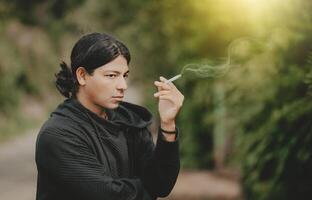 Portrait of handsome guy smoking outdoors. Young man smoking cigarette on the street photo