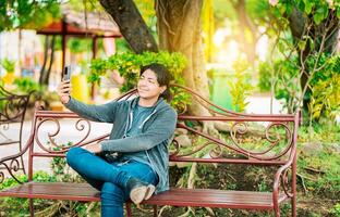 Smiling man sitting on a bench taking a selfie in Nagarote Park. Relaxed guy taking a selfie sitting on a bench in Nagarote Park photo