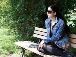 girl with sunglasses relaxing on park bench photo