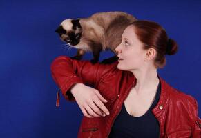 joven mujer jugando con gato en su brazo foto
