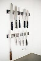 Set of professional knives on a white wall photo