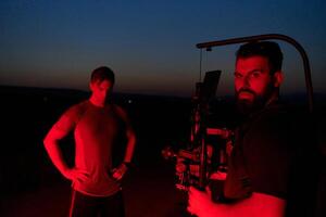 Nighttime Capture. Professional Videographer Films Athletes Running in Red-Lit Darkness photo