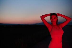 Athlete Strikes a Pose in Red-Lit Nighttime Glow photo