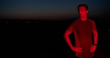 atleta huelgas un actitud debajo rojo Noche resplandor después intenso todo el día maratón. foto