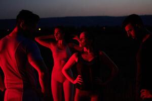 Diverse Athletes Unwind. Post-Marathon Rest Under Red Nighttime Glow. photo