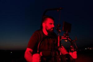 Noche captura. profesional camarógrafo Película (s Atletas corriendo en iluminado en rojo oscuridad foto