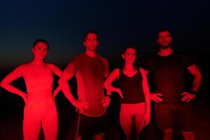 Diverse Athletes Unwind. Post-Marathon Rest Under Red Nighttime Glow. photo