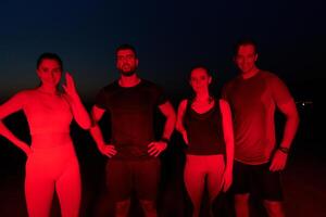 Diverse Athletes Unwind. Post-Marathon Rest Under Red Nighttime Glow. photo