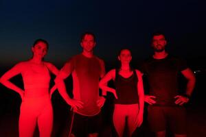 Diverse Athletes Unwind. Post-Marathon Rest Under Red Nighttime Glow. photo