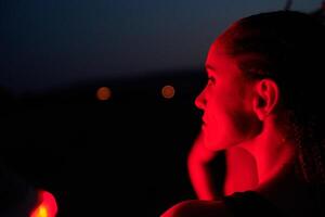 atleta huelgas un actitud en iluminado en rojo Noche resplandor foto