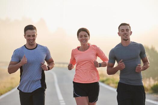 A group of friends, athletes, and joggers embrace the early morning hours as they run through the misty dawn, energized by the rising sun and surrounded by the tranquil beauty of nature photo