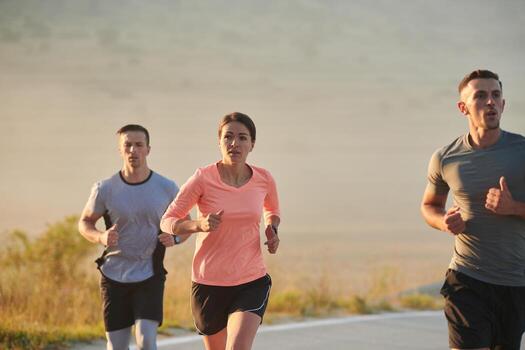 A group of friends, athletes, and joggers embrace the early morning hours as they run through the misty dawn, energized by the rising sun and surrounded by the tranquil beauty of nature photo