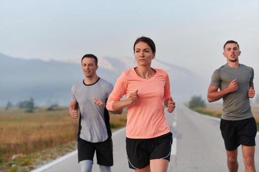 A group of friends, athletes, and joggers embrace the early morning hours as they run through the misty dawn, energized by the rising sun and surrounded by the tranquil beauty of nature photo